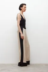 Pantalón ancho de lino color beige con paneles laterales negros y tajos en el ruedo.