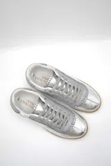 Zapatillas bajas color beige con detalles en marrón y cordones blancos.