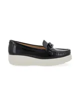 Mocasín de cuero charol negro con plataforma blanca y detalle de hebilla metálica plateada en el empeine.