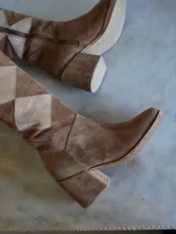 Botas altas de gamuza color marrón con diseño geométrico en tonos beige y marrón. Cierre lateral con cremallera y tacón cuadrado. Diseño exclusivo.