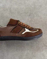 Sneakers bajas de cuero vacuno color bordó con suela marrón.