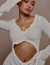 Minivestido blanco de mangas largas con volados, transparencias y abertura en el abdomen.