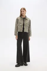 Chaqueta corta de jean con estampado animal print en tonos beige y gris, cuello camisero, cierre frontal con cremallera, bolsillos de parche en el pecho y corte entallado.