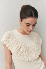 Chaleco color crema de tejido de punto, con cuello redondo y volados de crochet en el frente y la espalda.