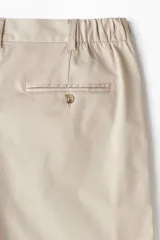 Short color beige de sarga de algodón suave, con elástico en los laterales de la cintura, cierre con botón, bolsillos al bies y bolsillos de atrás ribeteados con botón.