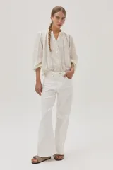 Blusa blanca de algodón con hilos metalizados, cuello mao y escote en V.