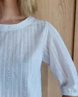 Remera blanca de algodón con mangas 3/4 abullonadas y cuello redondo. Presenta costuras a contratono en ruedo y cuello.