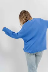 Sweater azul de punto medio, amplio, suave, con escote a la base y puños en mangas y en acabado inferior.
