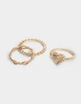 Set de tres anillos dorados con diferentes diseños: uno con forma de corazón calado, otro con eslabones entrelazados y otro con pequeñas esferas.