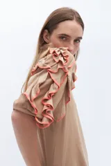 Remera color beige con mangas cortas y volados con borde naranja.