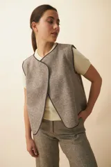 Chaleco marrón con solapas amplias y terminaciones envivadas. Diseño reversible y sin mangas.