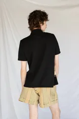 Camisa negra de manga corta con botones nacarados y corte estampado en el delantero.