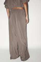 Pantalón palazzo color gris topo de tejido fluido, con cintura elástica ajustable con cordones y bolsillos laterales.