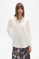 Blusa blanca de manga larga con cuello mao y escote en V con botones frontales.