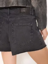 Short de jean negro con reverso de trama blanca, tiro medio, calce clásico y botamanga desflecada.