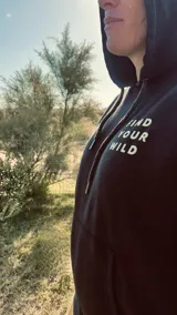 Hoodie negro con capucha y cordones ajustables, con estampado en la espalda de montañas, árboles, río y una camioneta con canoa en color blanco.
