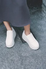Zapatillas blancas con plataforma gruesa, cordones y puntera redonda.