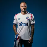 Camiseta de fútbol Umbro del Club Nacional de Football, modelo Home 2025, para hombre. Diseño blanco con detalles en azul y rojo en cuello y mangas. Incluye logo de Umbro, escudo del club y sponsor Antel en el frente.