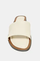 Sandalia plana color crema, de cuero, con detalle a contraste en la plantilla y punta redonda.