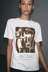 Camiseta blanca de algodón con cuello redondo, manga corta y estampado metalizado en el frente con formas abstractas y texto "AILGN92 SHAPES OF HARMONY".