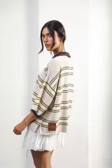 Remera de algodón y poliéster a rayas horizontales rojas y azul marino sobre fondo crudo. Tiene cuello tipo polo con botones, mangas amplias y corte oversized.