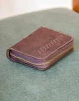 Billetera de cuero color tostado con cierre de cremallera. Interior con seis compartimentos para tarjetas y un compartimento para monedas con cierre. El billete entra doblado.