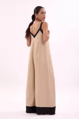 Mono palazzo color beige con terminaciones en negro, escote en V y tirantes anchos.