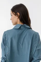 Camisa de tela terciopelada en color azul, con detalles de tablas laterales y bordado en la espalda.