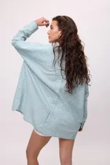 Camisa oversize a rayas verticales color amarillo y blanco, con cuello camisero, manga larga y cierre frontal con botones.