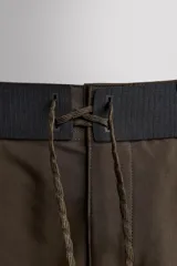 Bañador corto color marrón con cintura elástica negra ajustable con cordón. Tiene un bolsillo lateral con cierre de cremallera y costuras planas termofijadas.