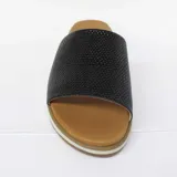 Sandalia con capellada de cuero negro con textura de piel de serpiente. Suela blanca con base marrón.