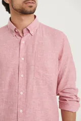 Camisa azul marino de lino y algodón, con cuello abotonado, manga larga con puños enrollados, bolsillo de parche en el pecho y cierre frontal con botones.
