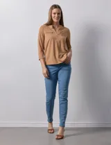 Blusa blanca de poliéster y elastano, con cuello a la base, escote en V y mangas tres cuartos. Presenta dos bolsillos frontales con cierre metálico dorado.