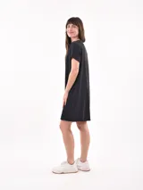 Vestido negro corto de corte recto, con cuello redondo y bolsillo en el pecho.