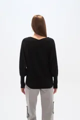 Sweater negro de tejido acanalado, corte holgado tipo murciélago con mangas largas ajustadas en puños. Escote bote adornado con apliques de pedrería plateada que se extienden por los hombros y mangas.