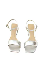 Sandalias de tacón medio plateadas, confeccionadas en cuero genuino, con tira ancha sobre los dedos y pulsera fina ajustable al tobillo.