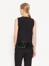 Chaleco corto color crudo, confeccionado en twill, con ruedo terminado en flecos de cuerina al tono y acceso delantero mediante botones forrados con tela base.