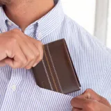 Billetera de cuero color gris oscuro con costuras decorativas en zigzag en tonos naranja y blanco en el exterior. El interior es de color gris oscuro y cuenta con compartimentos para billetes y tarjeteros con visor transparente.