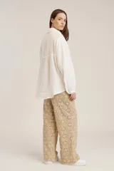 Camisa blanca de manga larga, corte holgado, con cuello camisero y detalles de bordados perforados (calado) verticales en el frente.