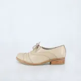 Zapato tipo Oxford color beige, con cortes calados y costuras, totalmente forrado de cuero, y cordones de algodón italianos.