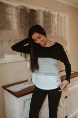 Remera de lactancia y embarazo de manga larga con diseño innovador en bloques de color: negro en la parte superior, beige a rayas horizontales en el medio y blanco en la parte inferior.