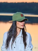 Gorra verde militar con visera curva y aplique de cuero con logo en el frente. Ajuste trasero con hebilla metálica.