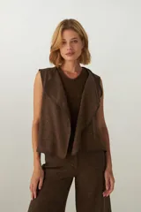 Chaleco marrón con solapas amplias y terminaciones envivadas. Diseño reversible y sin mangas.