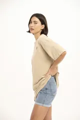 Remera marrón con cuello redondo, corte holgado y estampado pequeño de flores y texto en el pecho.