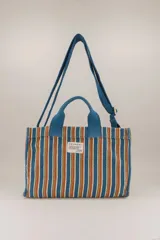 Bolso tote pequeño de algodón a rayas verticales en tonos azul, naranja, verde y blanco. Tiene doble asa corta azul y correa larga ajustable del mismo color.