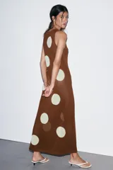 Vestido midi de tejido de punto color marrón, sin mangas y con cuello redondo. Presenta un estampado de lunares grandes en color crema/blanco roto.