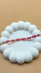 Pulsera de cuentas de piedra natural ágata en tonos rosados y verdes, con separadores de pequeñas esferas doradas.
