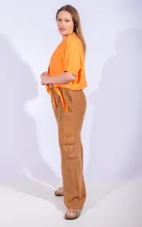Pantalón cargo naranja de lino, con cintura elástica ajustable con cordón y bolsillos laterales con solapa.