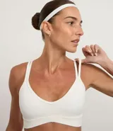 Top deportivo blanco de microfibra, con escote en V y tirantes finos que se cruzan en la espalda en forma de X.