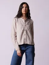 Chaqueta color beige de lino y rayón, con cuello mao, cierre frontal con botones y bolsillos delanteros.
